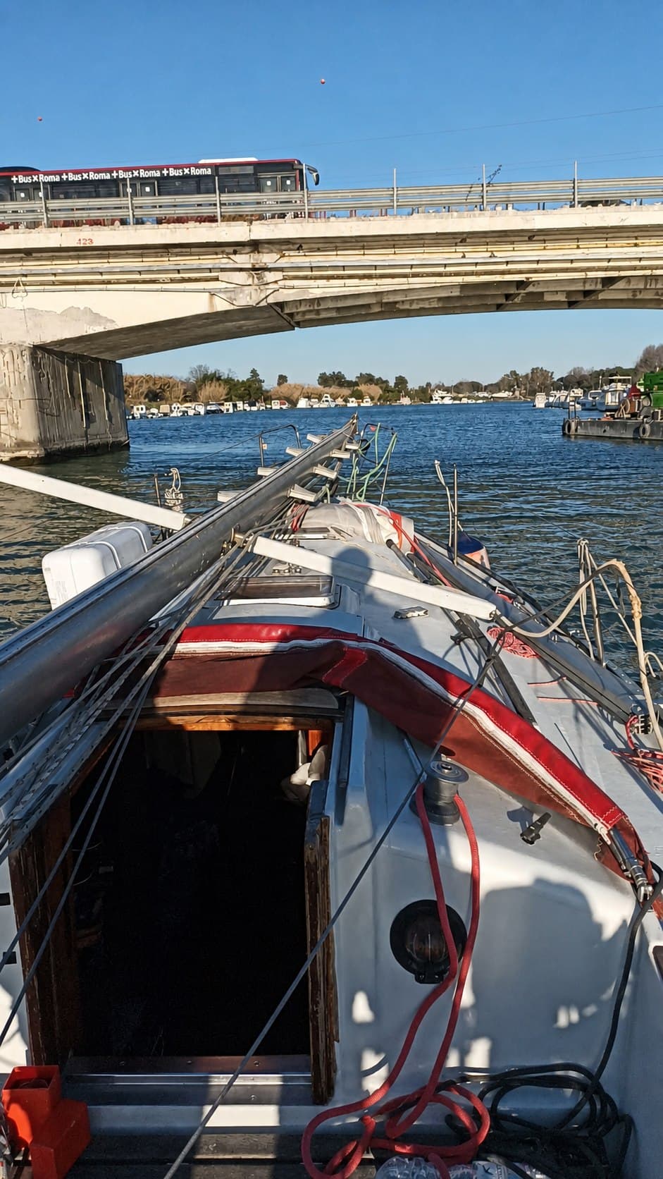 Barca a vela con albero disarmato durante il passaggio sotto un ponte a Fiumicino